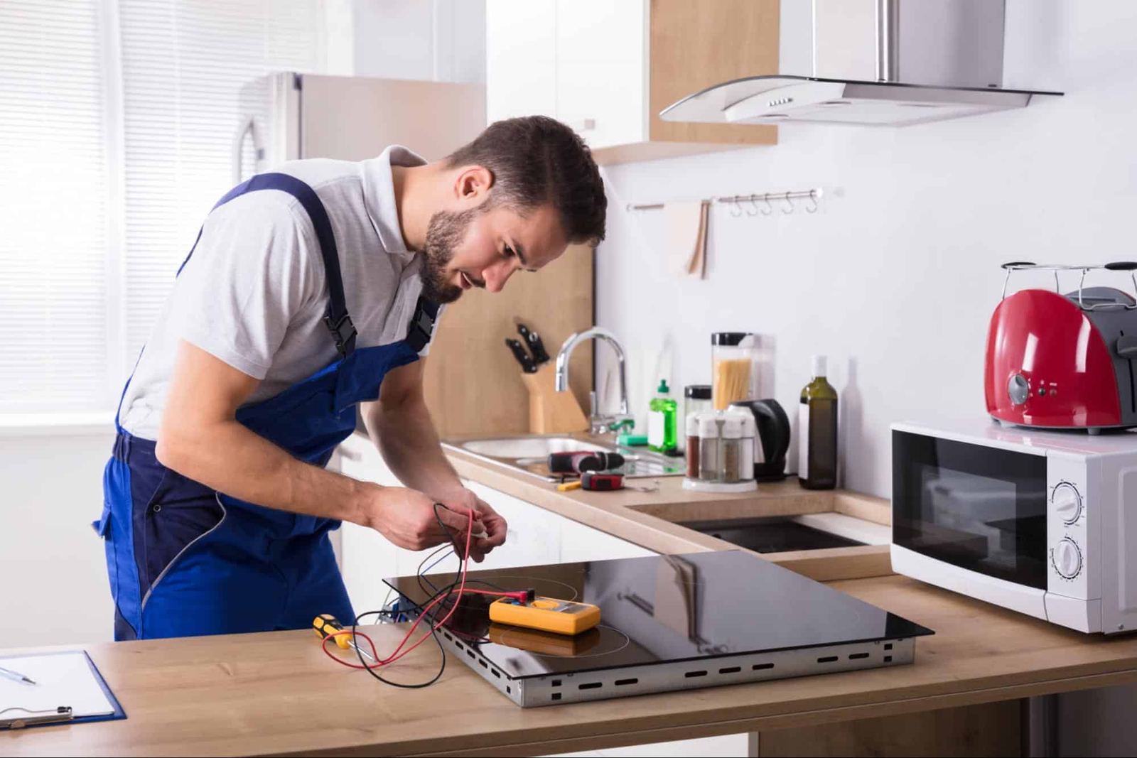 Technician testing a cooktop with a multimeter